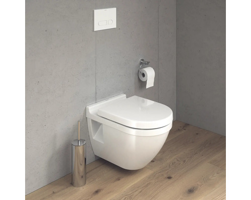 Wandhängendes WC mit Toilettenbürste und Toilettenpapierhalter an einer grauen Wand