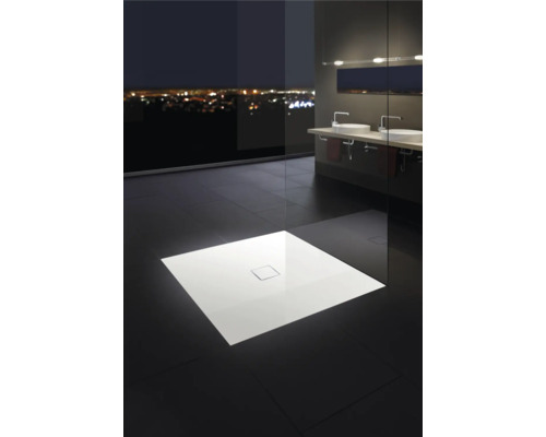 Salle de bains élégante avec receveur de douche plat, lavabos et baie vitrée donnant sur la ville de nuit.