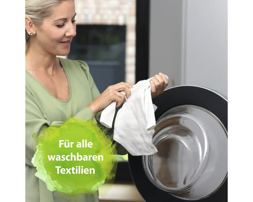 Une femme tient du linge devant une machine à laver. Convient à tous les textiles lavables.