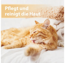 Un chat roux détendu prend soin de son pelage sur une couverture blanche.