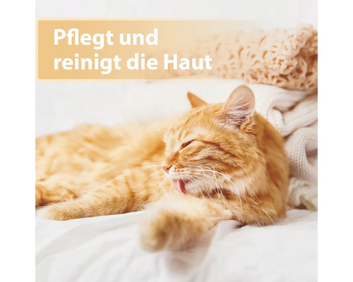 Un chat roux détendu prend soin de son pelage sur une couverture blanche.