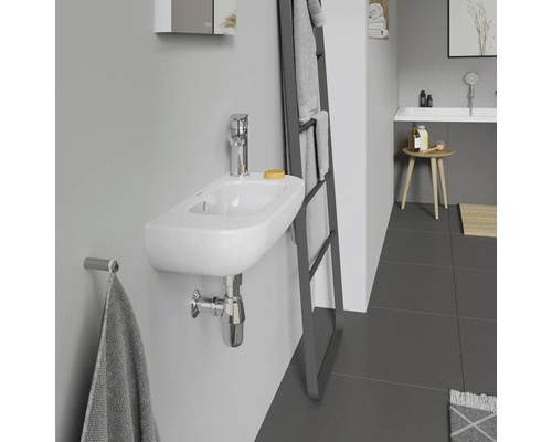 Salle de bain moderne avec un petit lavabo mural, robinetterie, porte-serviettes et échelle porte-serviettes