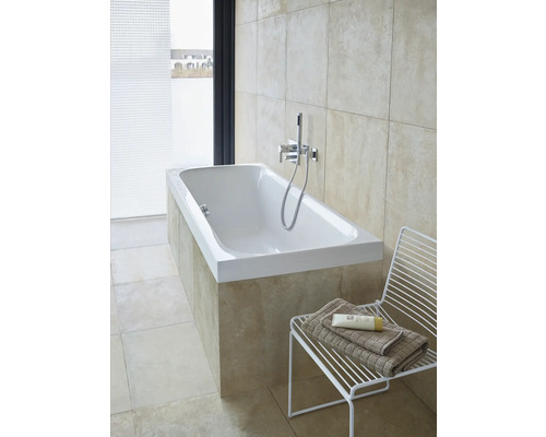 Salle de bain lumineuse avec baignoire intégrée, robinetterie et douchette