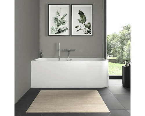 Badezimmer mit Badewanne, Armatur, Teppich und Wandbildern