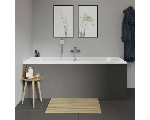 Salle de bains avec baignoire, robinetterie, pomme de douche, tabouret de bain, tapis de bain et décoration