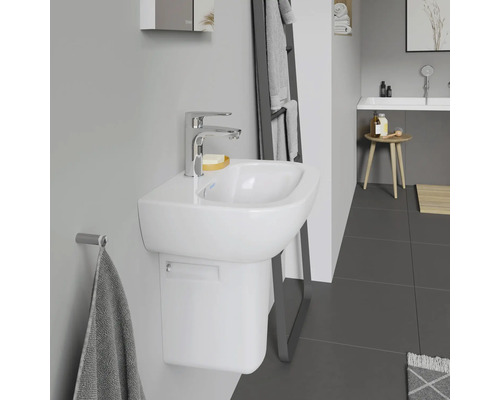 Badezimmer mit weißem Waschtisch, Armatur und Handtuchhalter.