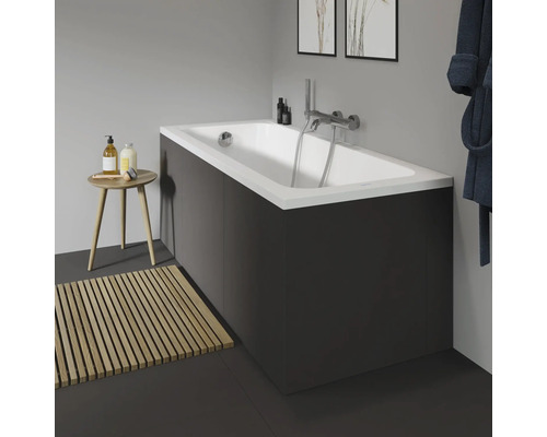 Salle de bains avec baignoire, robinetterie, tapis de bain en bois et tabouret