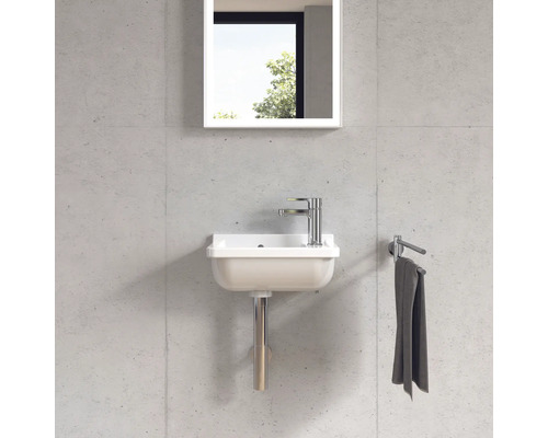 Kompaktes Waschbecken mit Armatur, Spiegel und Handtuchhalter an einer Wand montiert.