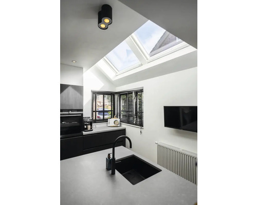 Moderne Küche mit Dachfenstern, Spüle, Armatur, Heizkörper und schwarzem Mobiliar.