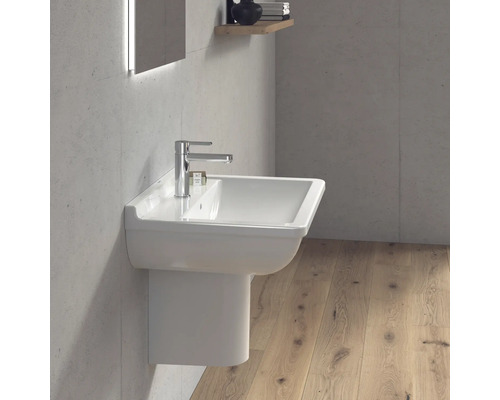 Salle de bain moderne avec un lavabo blanc et robinet sur un mur en béton.