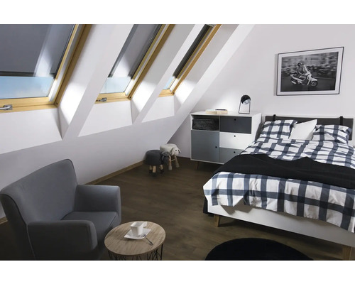 Helles Schlafzimmer im Dachgeschoss mit Dachfenstern, Bett, Sessel und Kommode