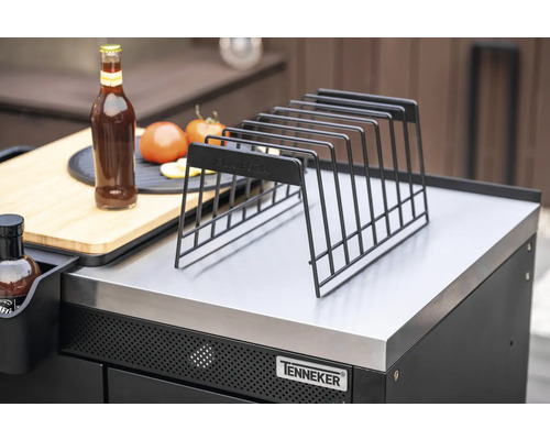 Grille de rangement en métal sur un poste de grill avec bouteille, tomates et planche à découper