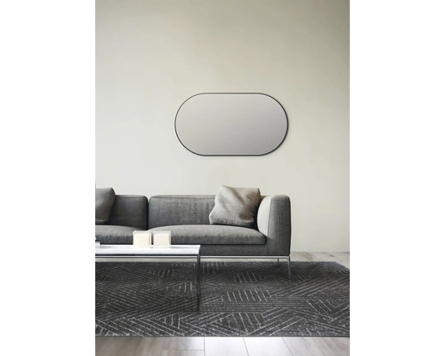 Salon avec miroir mural ovale au-dessus d''un canapé gris