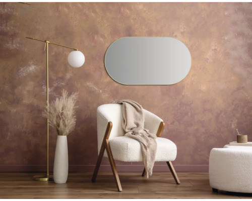 Salon avec fauteuil, miroir, lampadaire, tabouret et vase avec des herbes décoratives pour une ambiance chaleureuse.