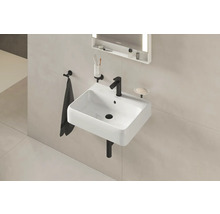 Lavabo avec robinet, serviette, porte-savon et miroir éclairé dans la salle de bains.
