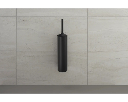 Brosse de toilette noire devant un mur carrelé