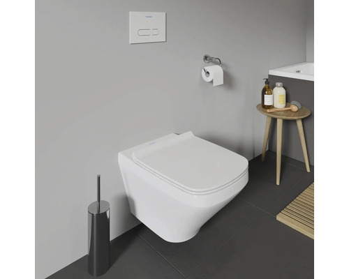 WC suspendu dans une salle de bains avec une brosse de toilette et un porte-papier toilette