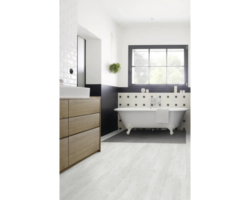 Salle de bains avec baignoire îlot, lavabo et fenêtre pour une ambiance lumineuse.