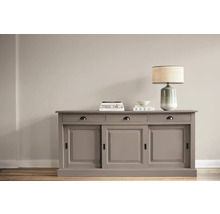 Commode avec portes coulissantes, tiroirs, lampe et décoration sur un plancher en bois