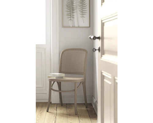 Laque Alpina Feine Farben Berceau de l'arôme gris-beige raffiné 750 ml Chaise avec dossier en rotin et livre sur l''assise devant une décoration murale