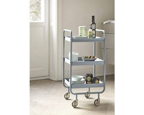 Chariot de service à trois niveaux avec roulettes, chargé de vaisselle et de produits alimentaires.