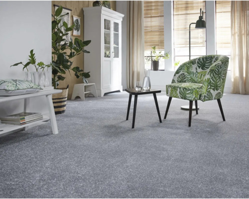 Espace de vie lumineux avec moquette, fauteuil à motif de plantes et objets de décoration
