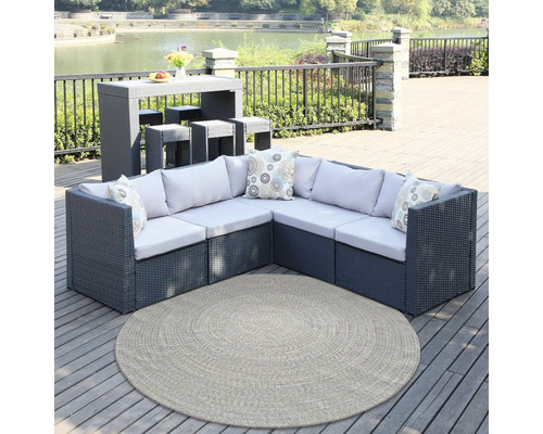 Gartenmöbel-Set mit Tisch, Hockern, Ecksofa, Kissen und rundem Teppich auf einer Terrasse am See