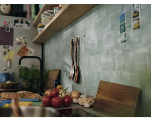 Küchenszene mit Regalen, Kochutensilien und frischen Zutaten auf der Arbeitsfläche.