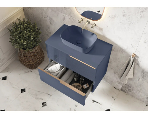 Salle de bains moderne avec meuble-lavabo bleu, vasque à poser et tiroir ouvert pour ranger les accessoires de salle de bains.