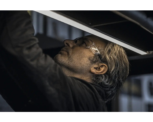 Un homme portant des lunettes de sécurité installe une lampe LED.