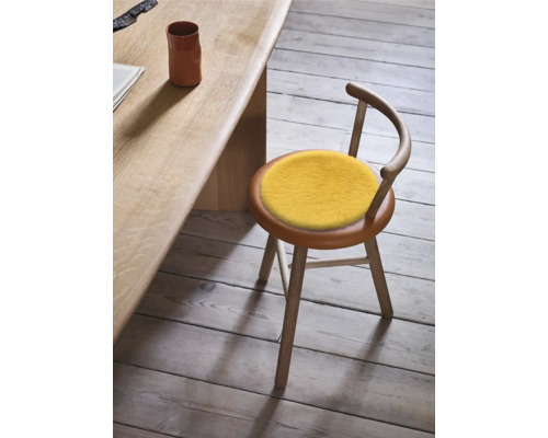 Holzstuhl mit gelbem Sitzkissen neben einem Holztisch