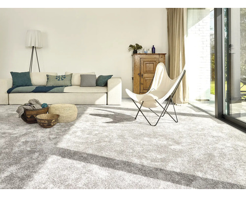 Espace de vie lumineux avec moquette, canapé, fauteuil et éléments en bois pour une ambiance conviviale