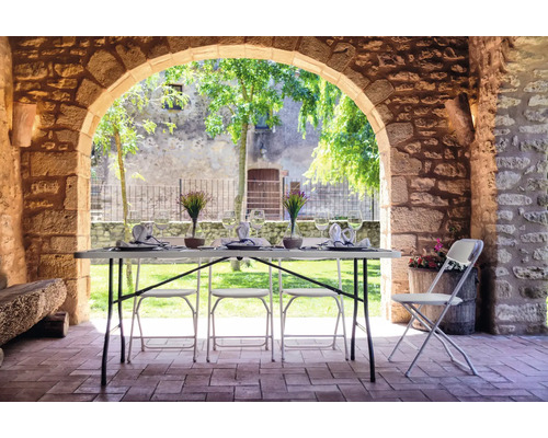 Gedeckter Tisch und Stühle auf einer Terrasse unter einem Steingewölbe