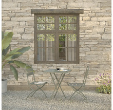 Scène de jardin avec table, deux chaises et plantes devant un mur de pierre