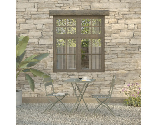 Scène de jardin avec table, deux chaises et plantes devant un mur de pierre