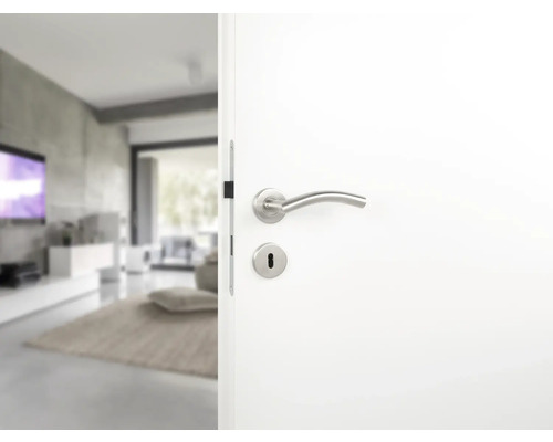 Weiße Innentür mit Türgriff und Schlüsselloch, die in ein modernes Wohnzimmer führt