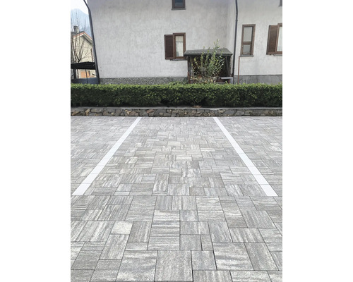 Aussenbereich mit Pflastersteinen und Parkplatzmarkierungen vor einem Gebäude