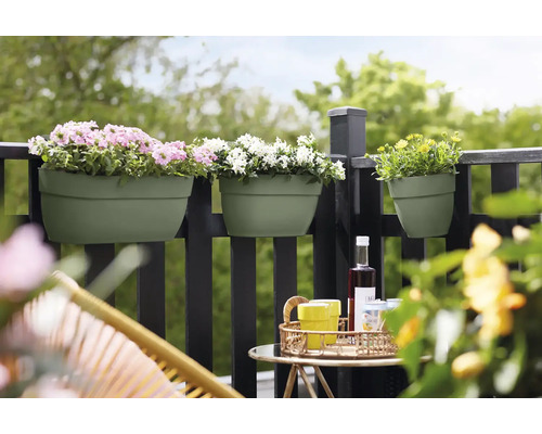 Balkonszene mit Blumenkästen an einem Geländer, bepflanzt mit rosa, weißen und gelben Blumen, mit einem Tisch und Stühlen im Vordergrund