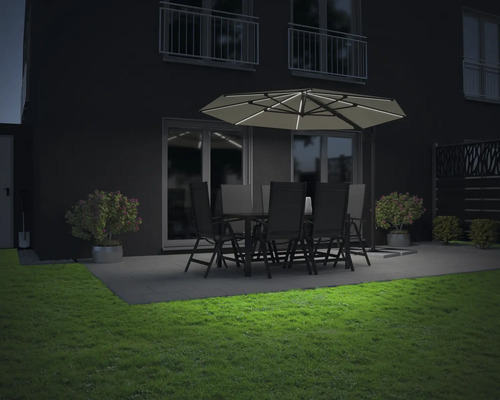 Gartenszene mit beleuchtetem Sonnenschirm, Gartentisch und Stühlen auf einer Terrasse bei Nacht