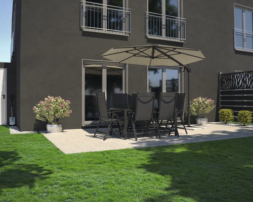 Gartenszene mit Esstisch, Stühlen und Sonnenschirm auf einer Terrasse neben einem Rasen