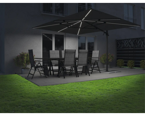 Gartenmöbelset unter einem beleuchteten Sonnenschirm auf einer Terrasse mit Rasen