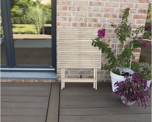 Table pliante en bois sur une terrasse à côté de plantes