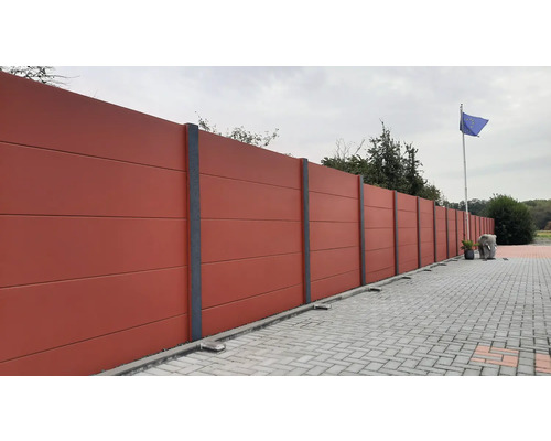 Longue clôture en béton avec piliers gris et pavés