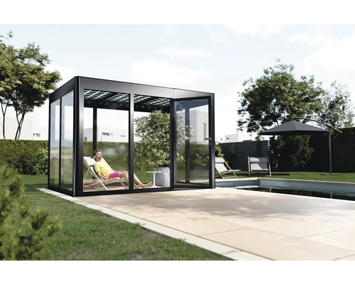 Maison de jardin moderne avec portes coulissantes en verre et homme allongé sur une chaise longue