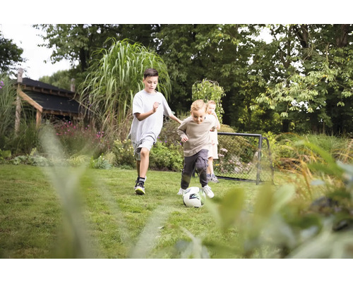 Kinder spielen Fußball im Garten mit Fußballtor