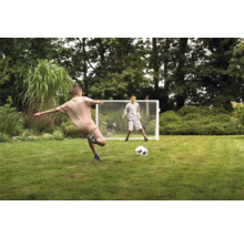 Zwei Jungen spielen mit einem Fußballtor im Garten.