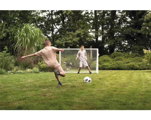 Deux garçons jouent avec un but de football dans le jardin.