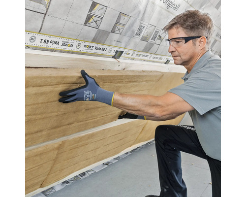 Artisan installant un matériau isolant sur un mur