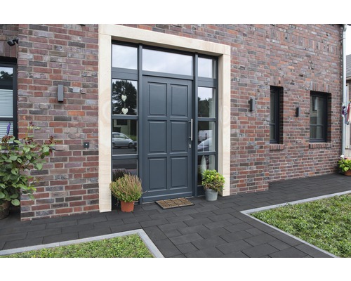 Haustür mit Seitenteilen und Oberlicht in einem Backsteinhaus mit Pflastersteinen