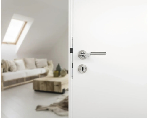 Weiße Innentür mit silberfarbener Türklinke zu einem hellen Wohnzimmer